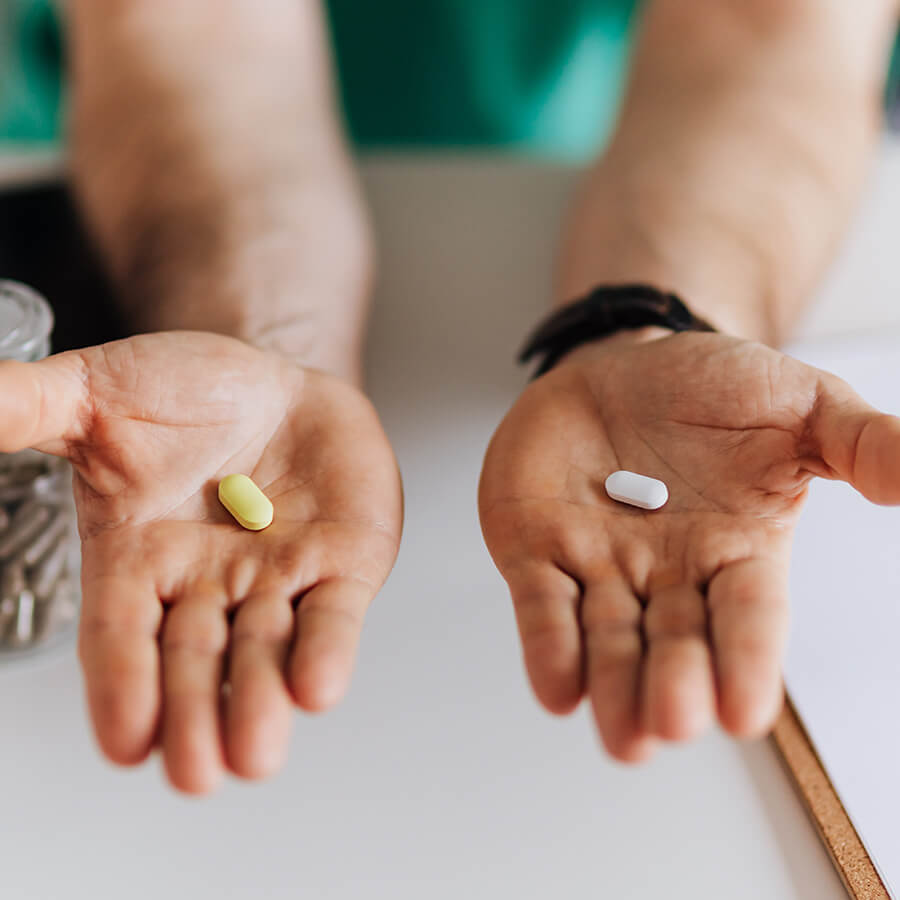 doctor holding 2 different pill options in his hands